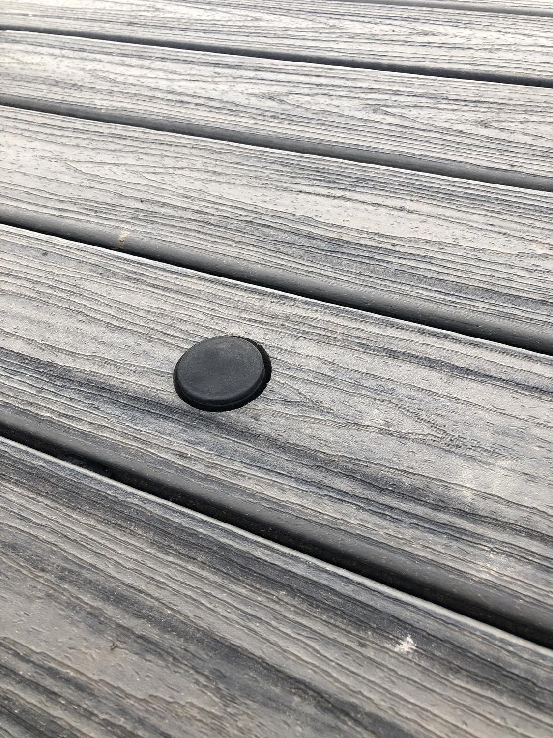 Protective cap covering empty Patio Buddy sleeve flush with deck