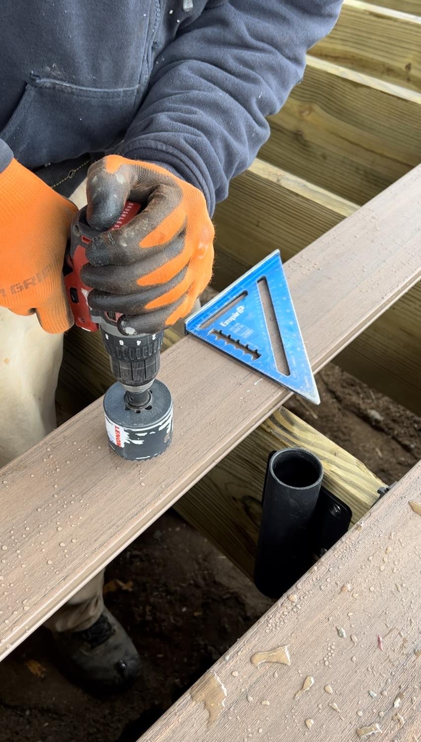 Drilling a hole in deck board with a hole saw