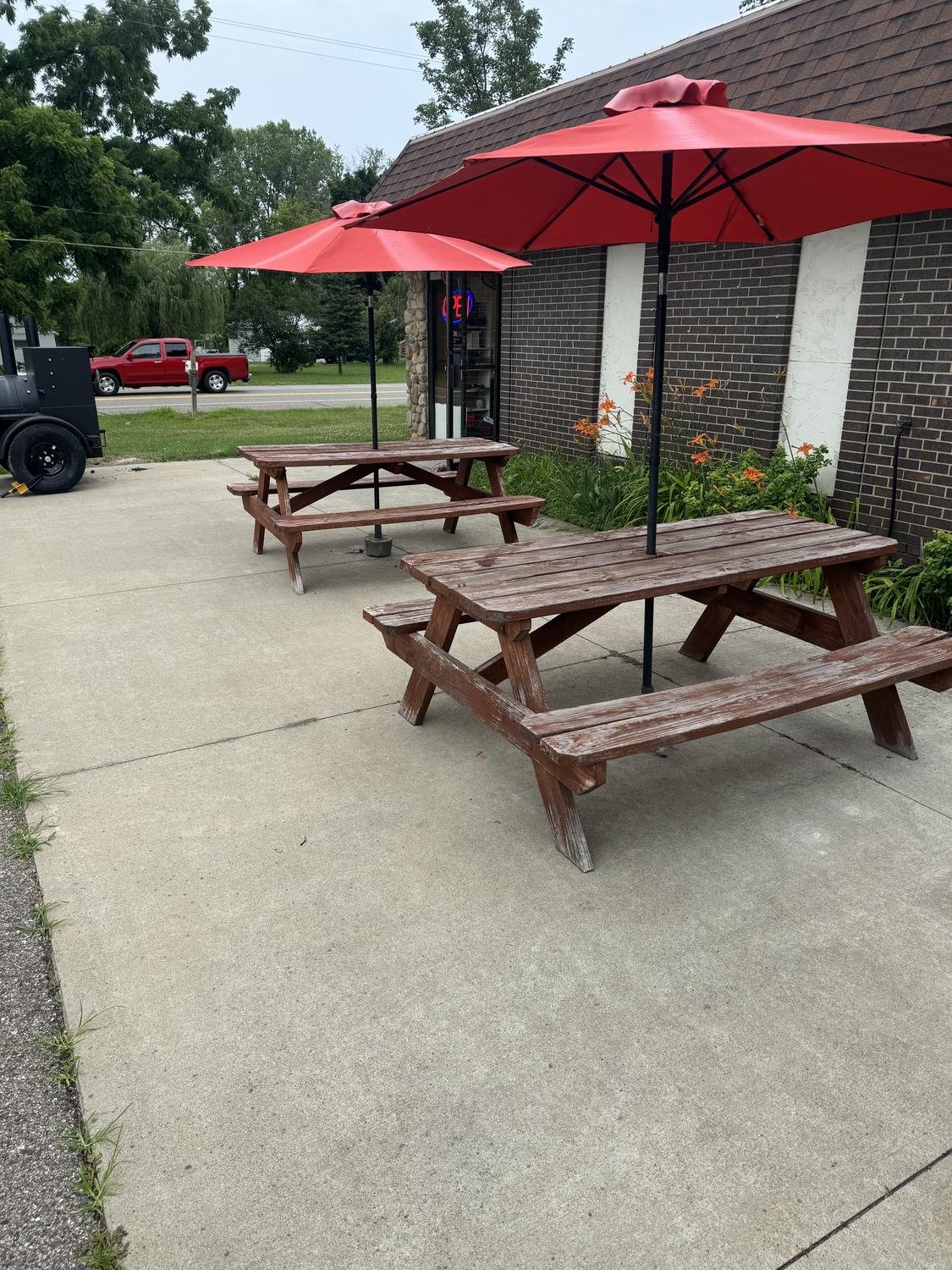 Commercial picnic tables with red umbrellas mounted