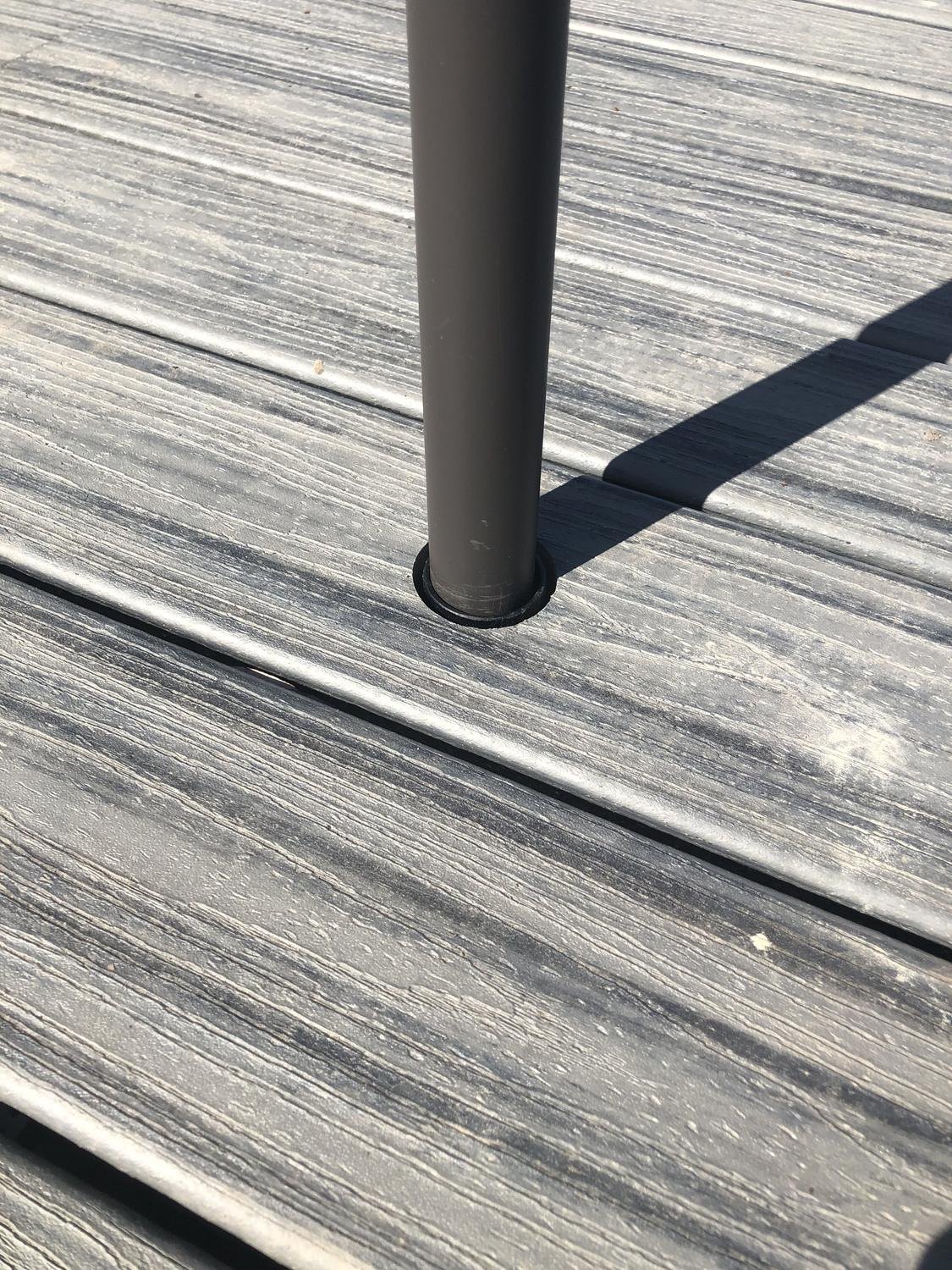 Umbrella pole sitting flush in a deck-mounted Patio Buddy sleeve