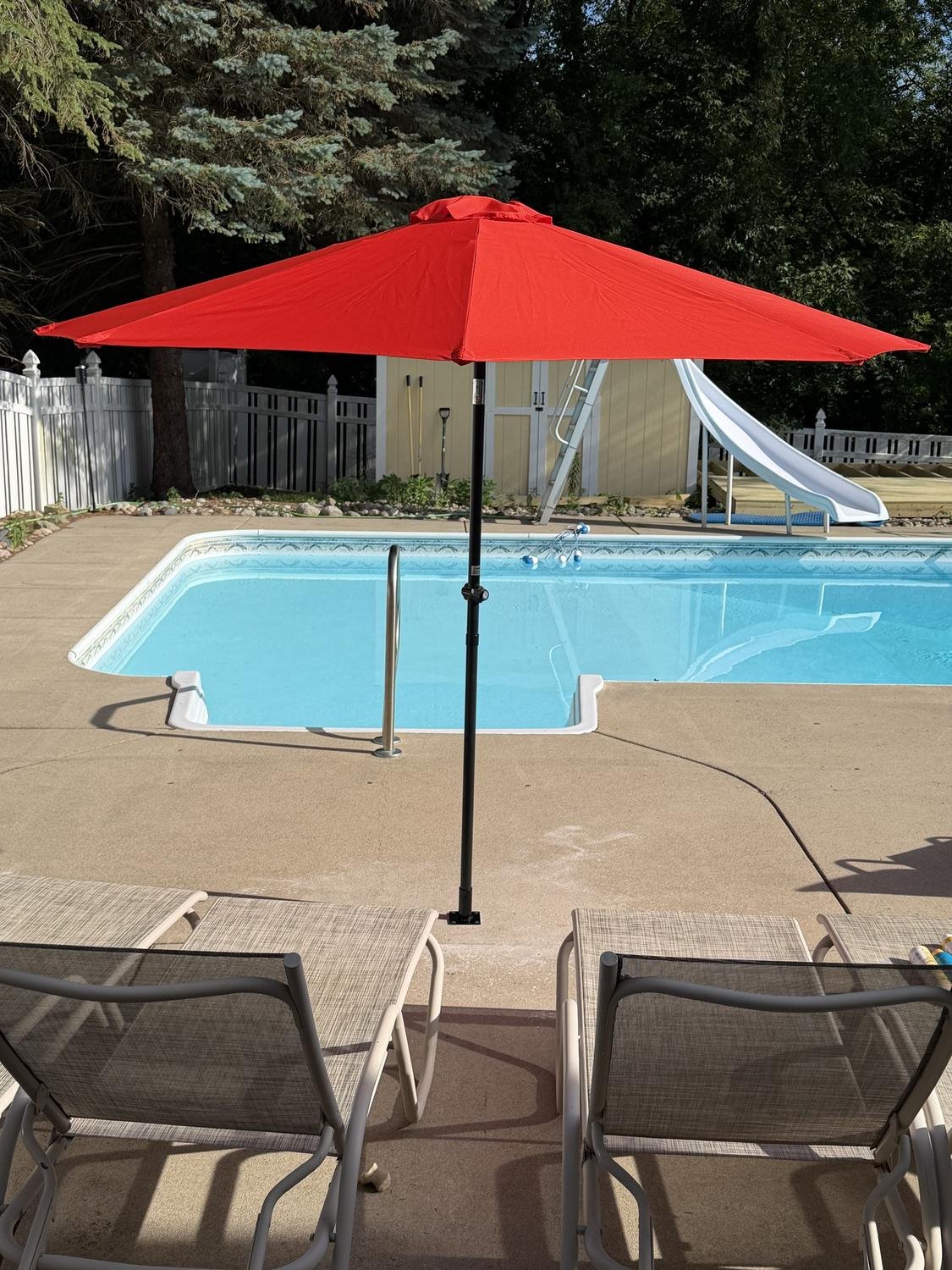 Red umbrella mounted beside a swimming pool
