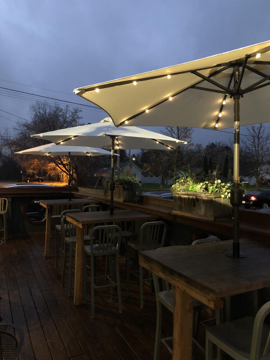 Restaurant patio with lit umbrellas mounted to high-top tables