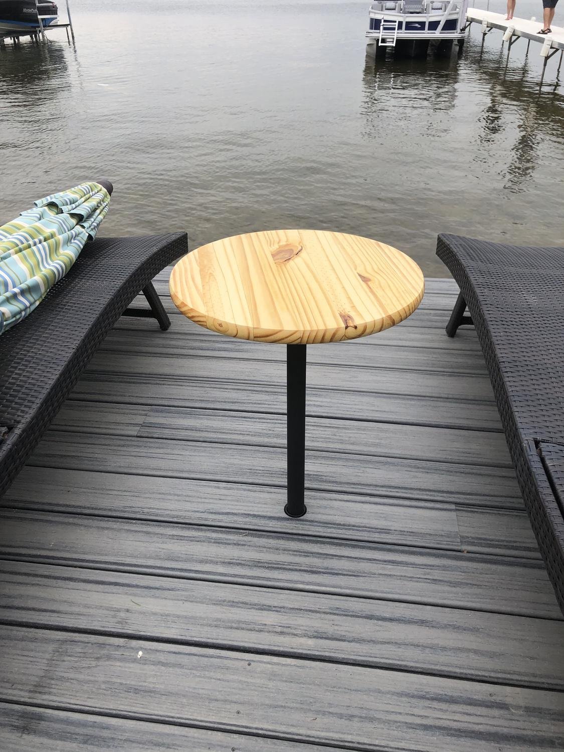 Round wooden side table mounted in a deck sleeve